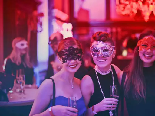 Three friends in masquerade masks raising glasses